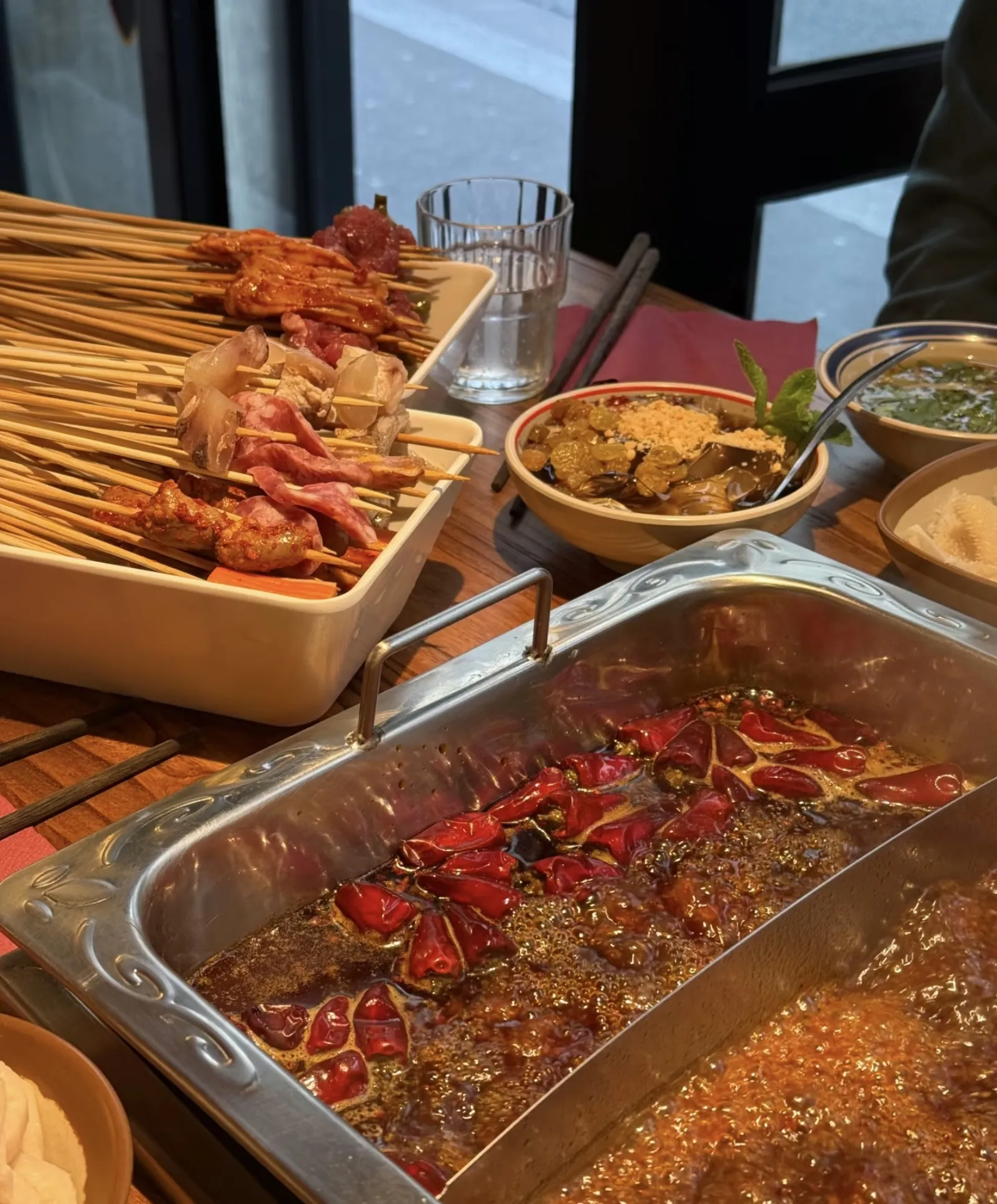 Marmite rouge bouillonnante avec brochettes plongées dans le bouillon pimenté